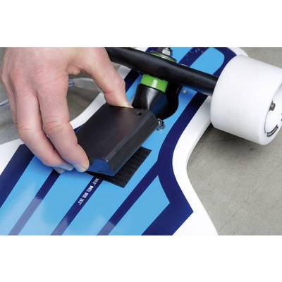 Une personne fixe un objet rectangulaire sous un longboard bleu. Le focus est mis sur la main et l'objet.