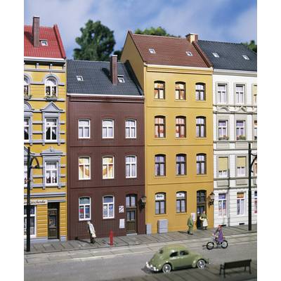 Une rue de ville miniature avec des bâtiments colorés, des passants et une coccinelle verte Volkswagen sur la route. La scène semble vivante et détaillée.