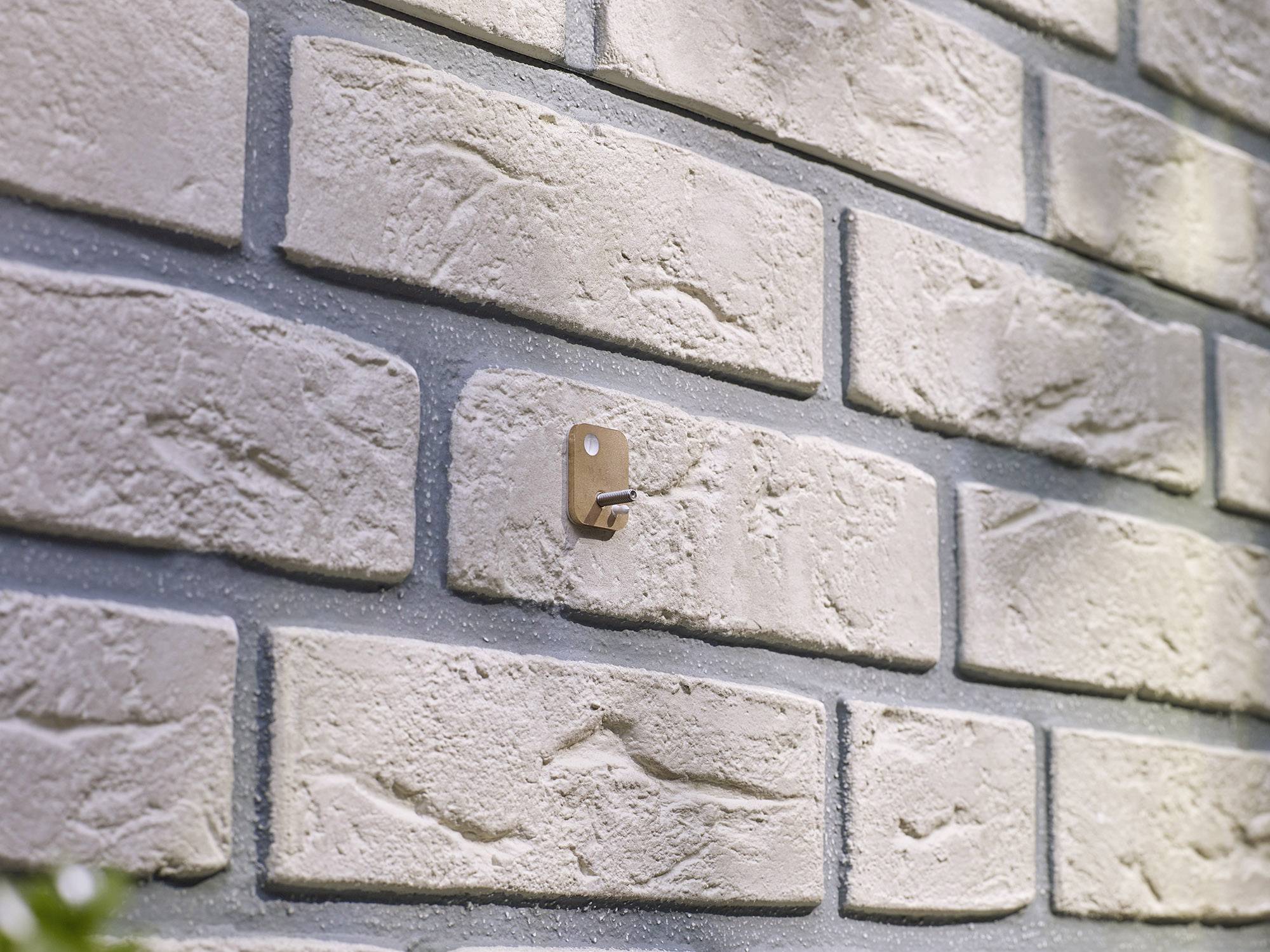 Gros plan sur un mur de briques structuré avec un petit crochet métallique sur l'une des briques.