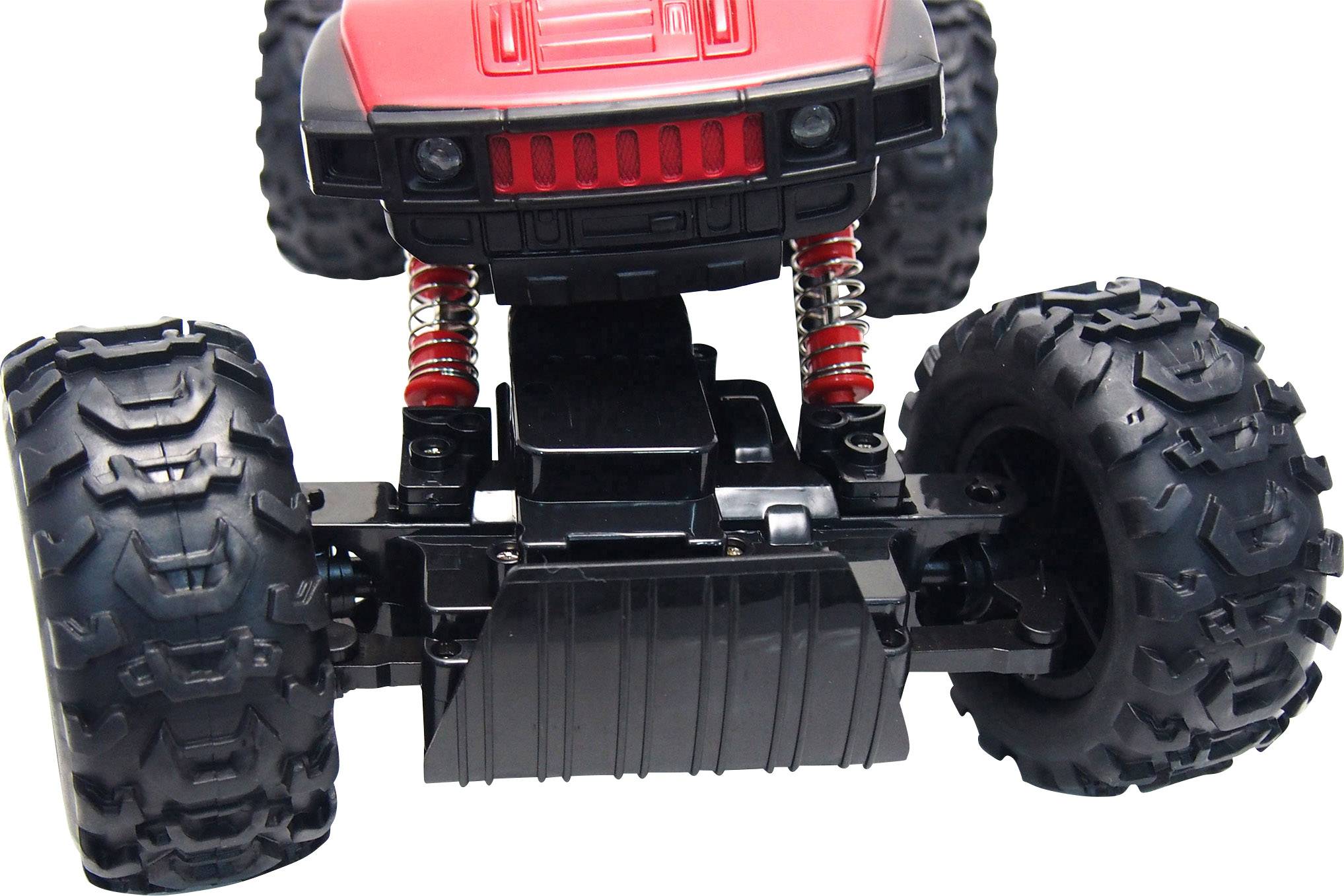 Gros plan d'une voiture télécommandée rouge avec de grandes roues robustes et des ressorts rouges sur sa suspension.