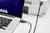 Un ordinateur portable est connecté à une imprimante via un câble USB, ce qui suggère un processus d'impression ou un transfert de données.