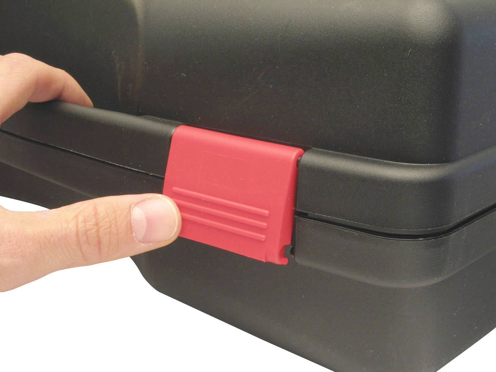 'Une main appuie sur un verrou rouge d'une valise noire en plastique.'