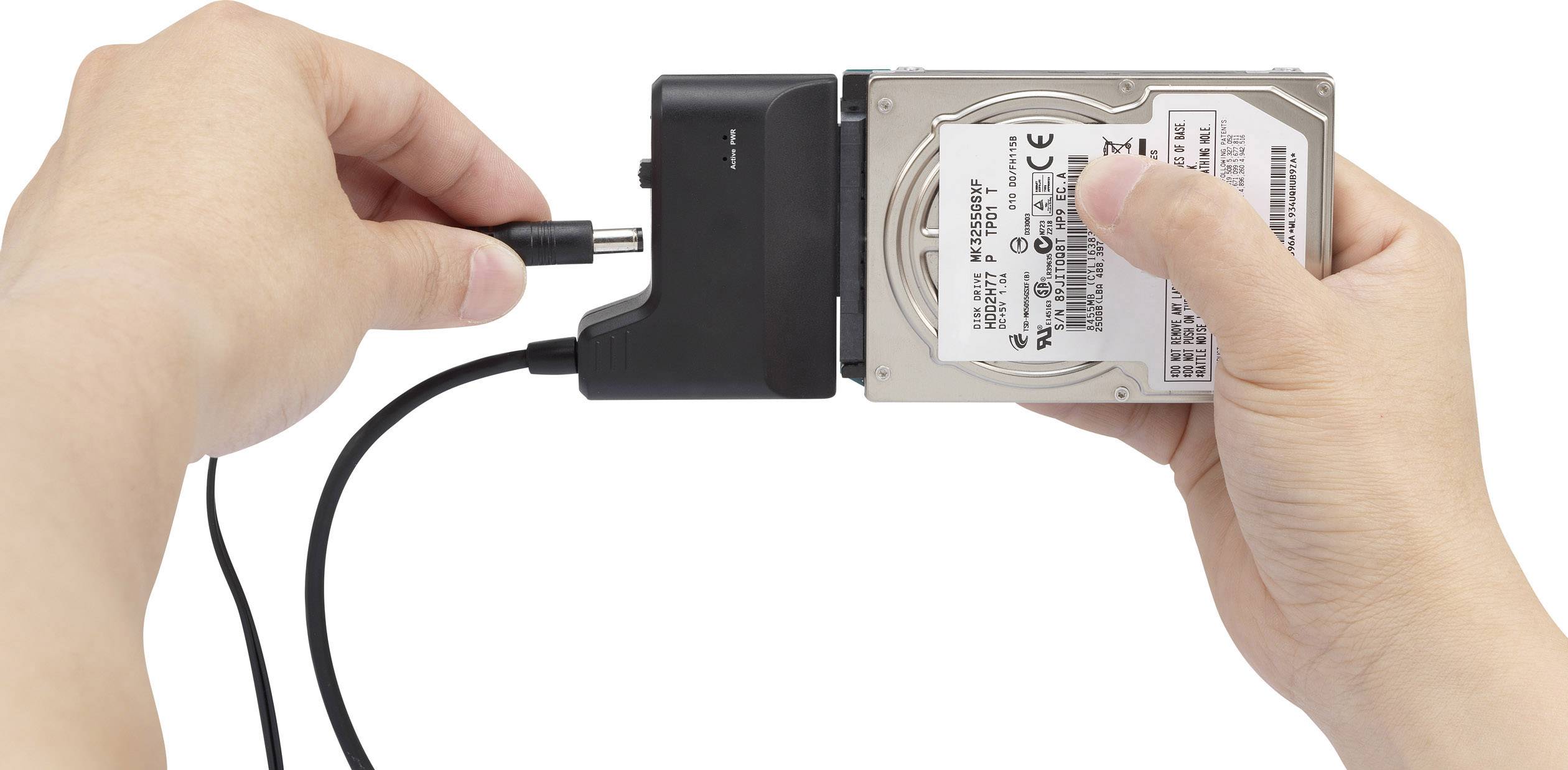 Une personne tient un disque dur et le connecte avec un câble réseau. Elle prépare un branchement de disque dur externe.