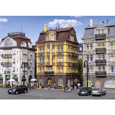 Rue bordée de bâtiments historiques, aux façades richement ornementées, avec des voitures passant et des piétons ; scène urbaine typiquement européenne.