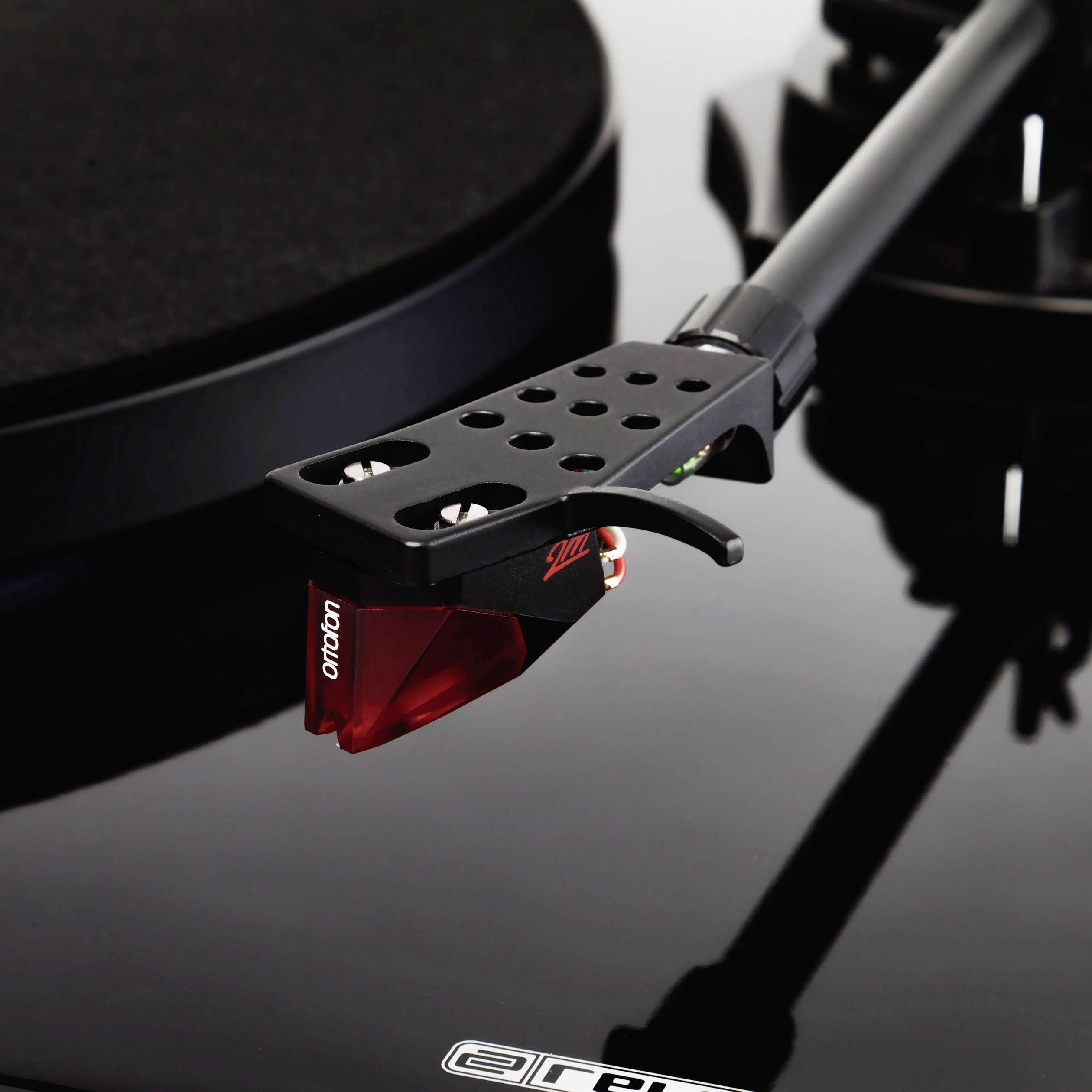 Tourne-disque avec cellule rouge et bras de lecture noir, illustrant précision et élégance. Parfait pour les mélomanes et les audiophiles.