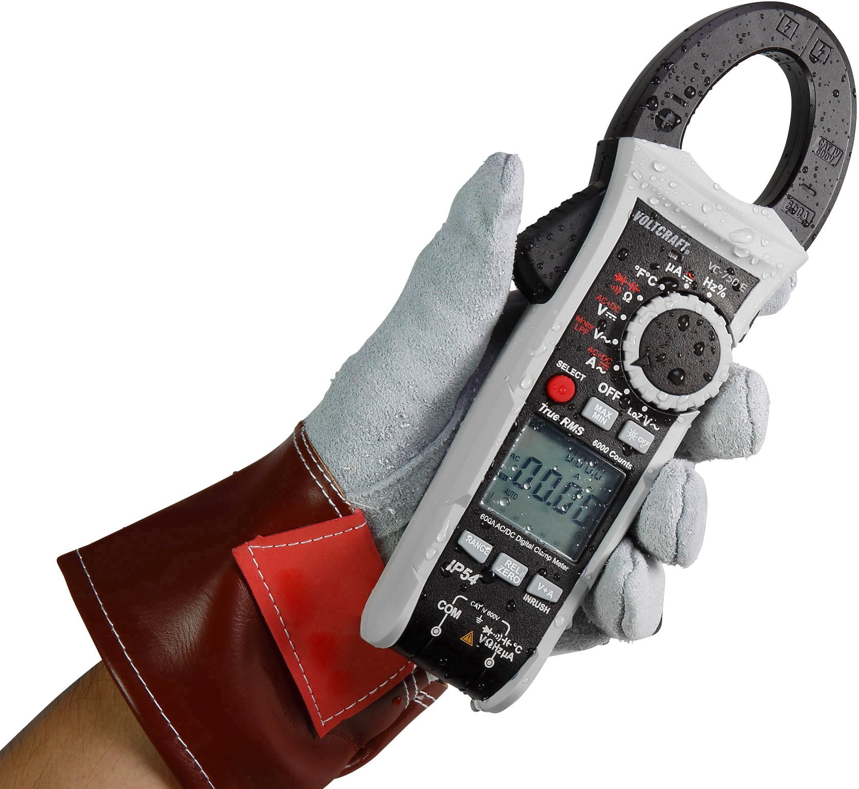 Une main gantée tient un multimètre numérique à pince. L'écran affiche '0,00'. L'appareil mesure les valeurs électriques.