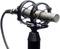 Un microphone argenté dans un support, relié par un câble, est dressé verticalement. Il pourrait être utilisé pour des enregistrements sonores.