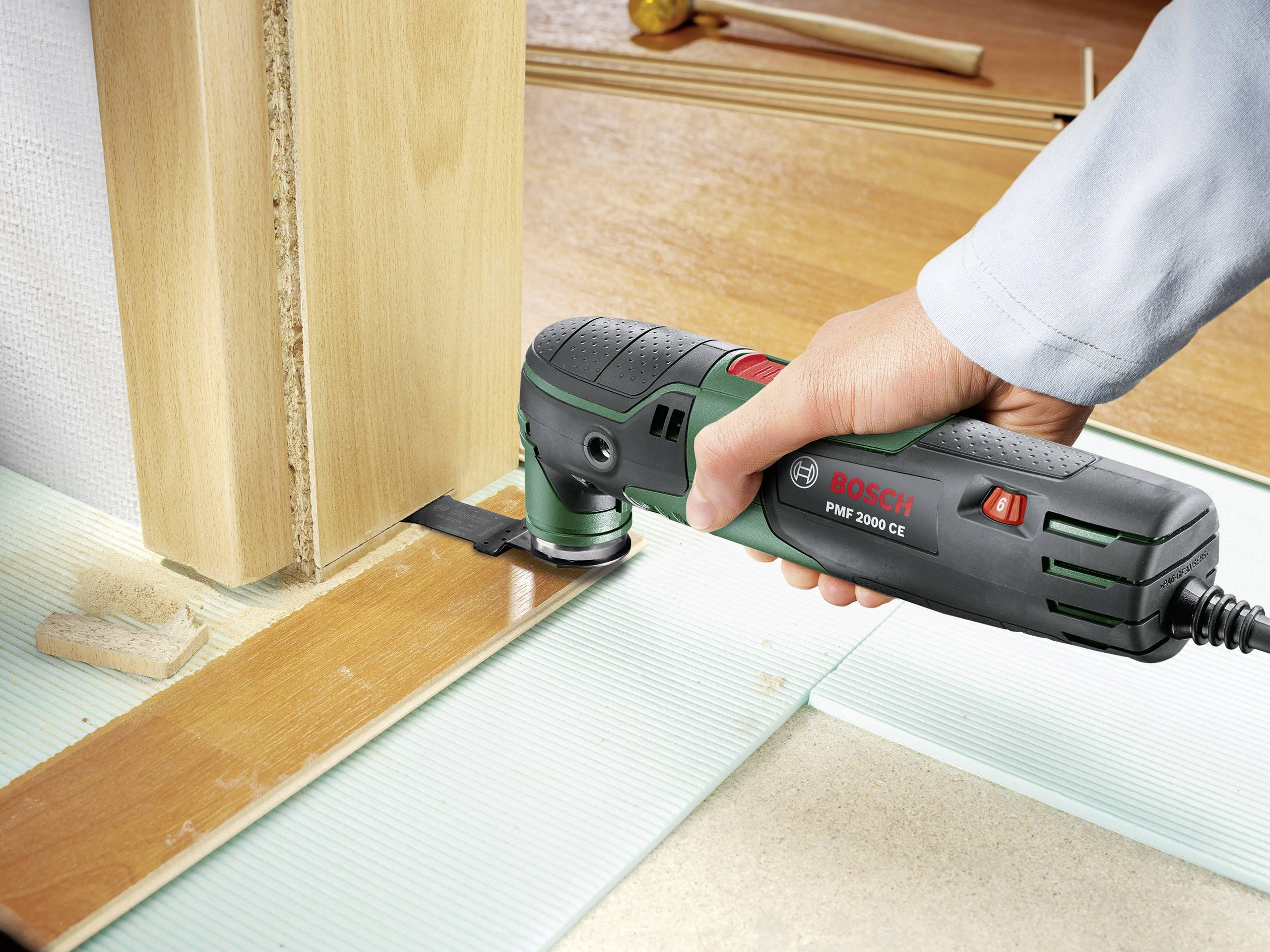 Une personne utilise un outil multifonction Bosch pour couper précisément des pièces en bois. L'appareil est placé au bord d'un morceau de bois.