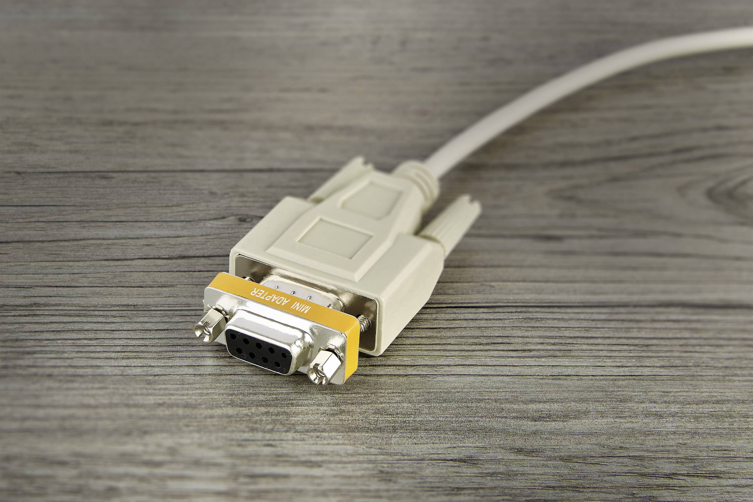 Un câble VGA blanc avec un ruban orange portant l'inscription « Null modem » est posé sur une surface en bois.
