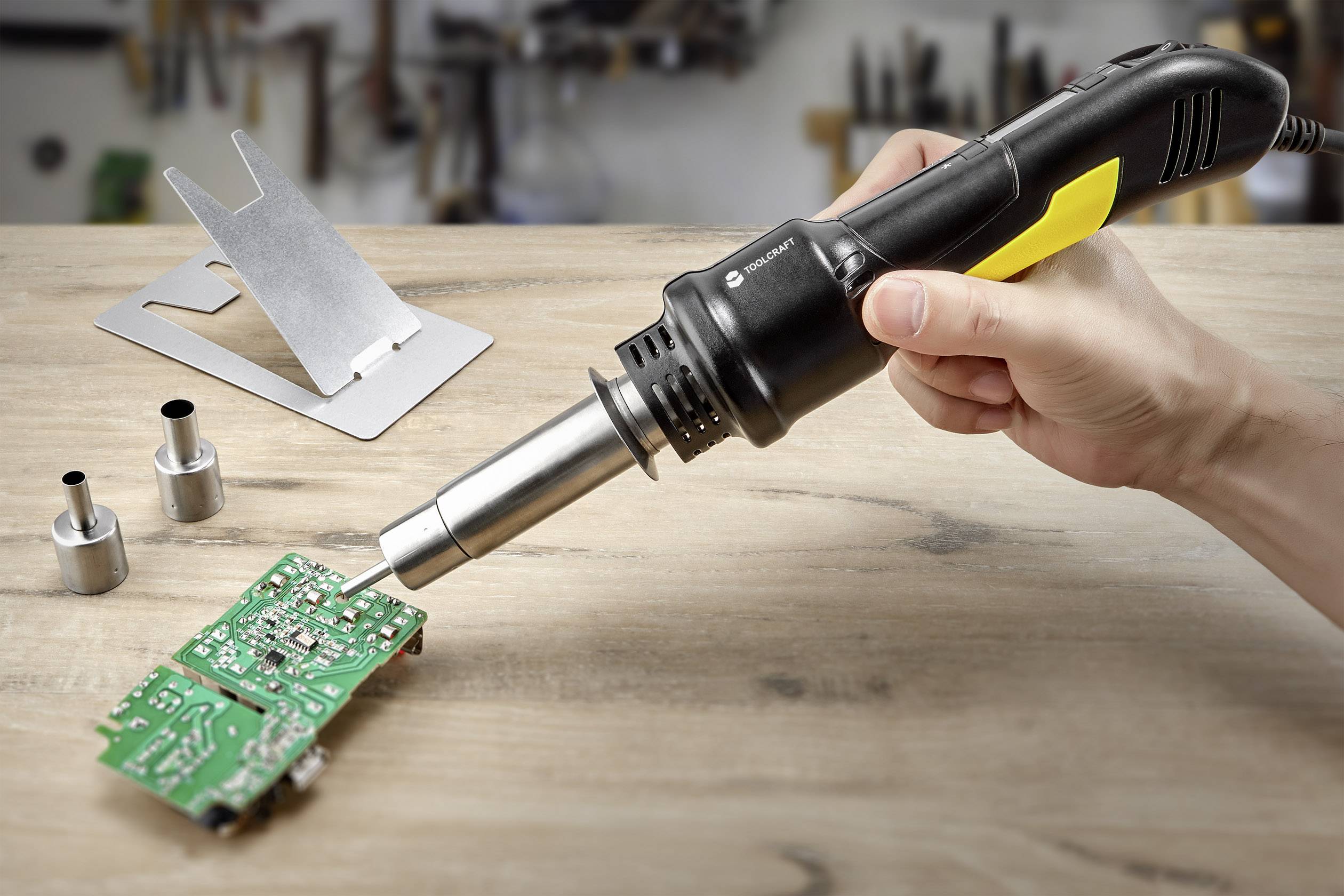 Une personne soude une carte électronique verte à l'aide d'un fer à souder. L'arrière-plan montre des outils flous.