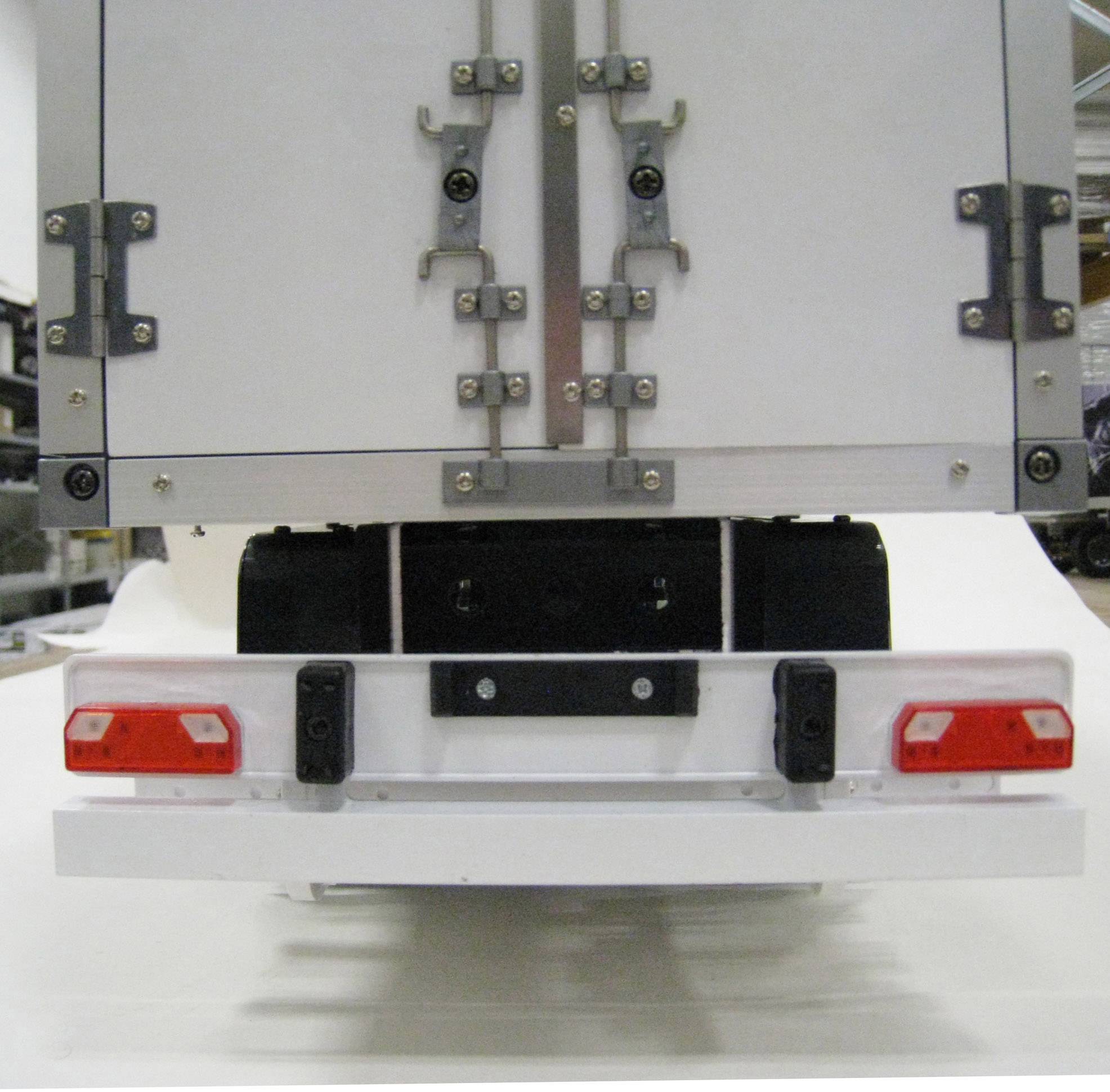 Un camion blanc vu de dos avec une vue de la porte fermée. Les feux arrière sont rouges et montés sur le bord inférieur du véhicule.