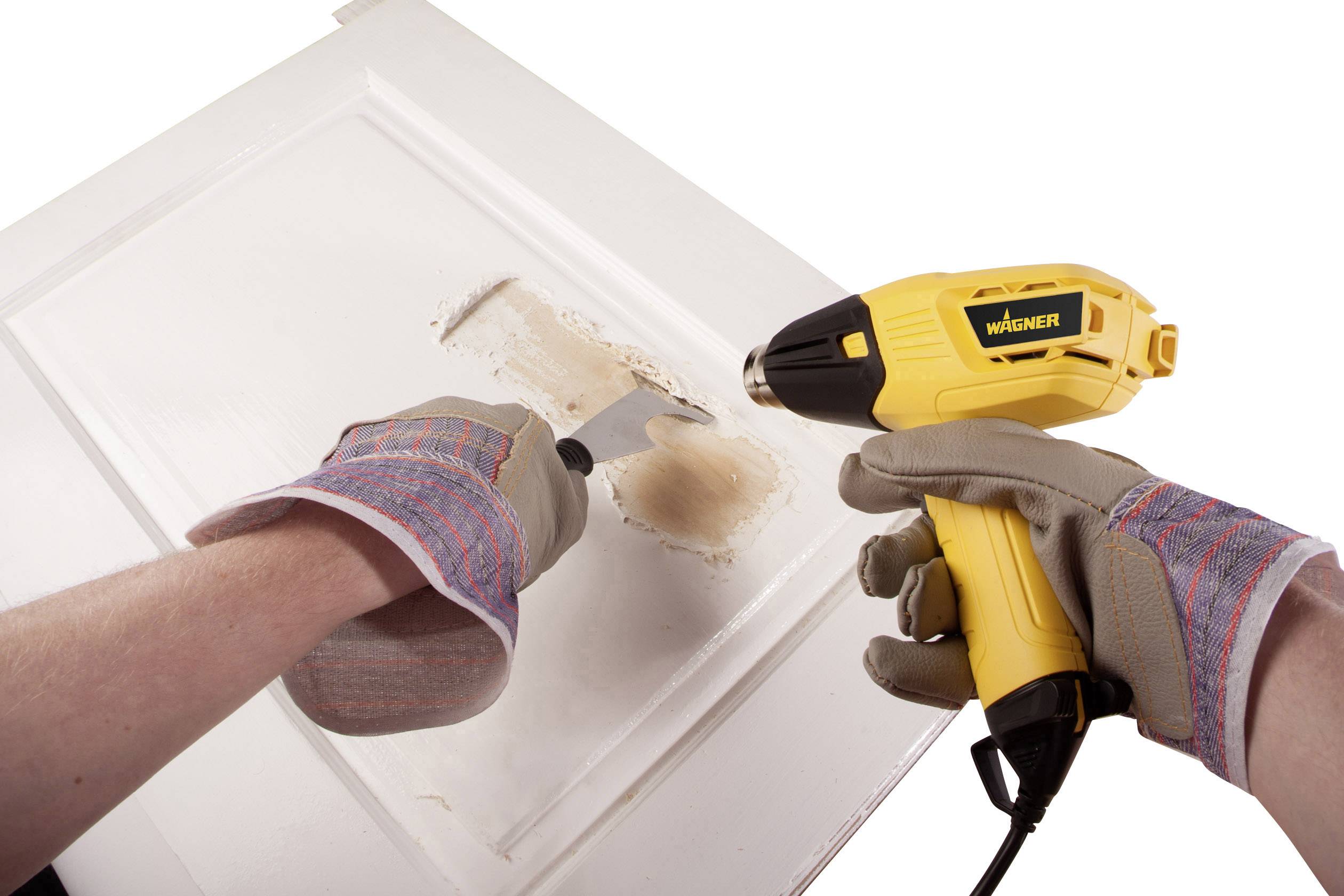 Une personne retire de la peinture d'une porte en bois blanche à l'aide d'une spatule et d'un pistolet à air chaud.