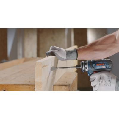 Une personne utilise une perceuse à percussion Bosch bleue, alimentée par batterie, pour percer un trou dans une planche en bois. Porter des gants.
