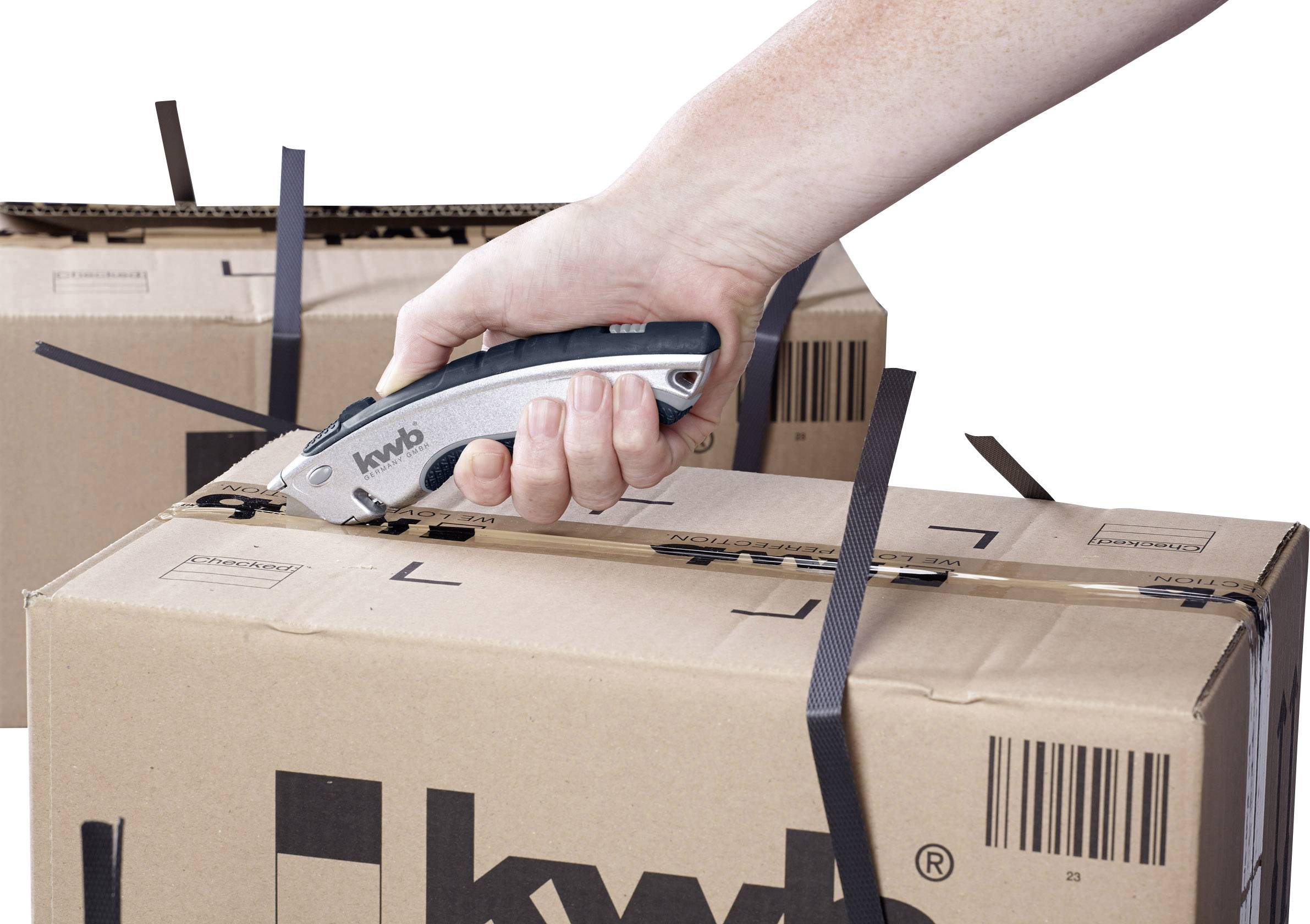 Une main tient un couteau à lame rétractable et coupe des colliers de serrage noirs sur un carton imprimé 'kwb'.