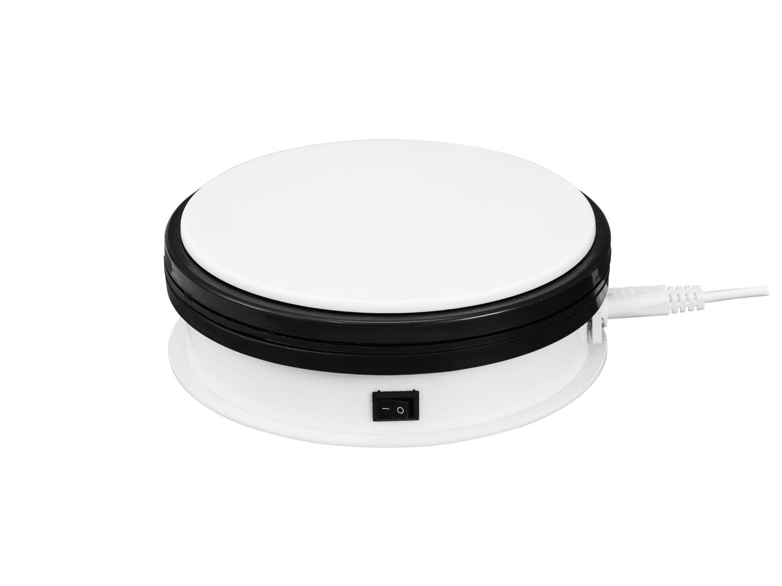 Chauffe-plat électrique blanc et rond, avec un bord noir et un interrupteur à bascule sur l'avant, relié à un cordon d'alimentation.