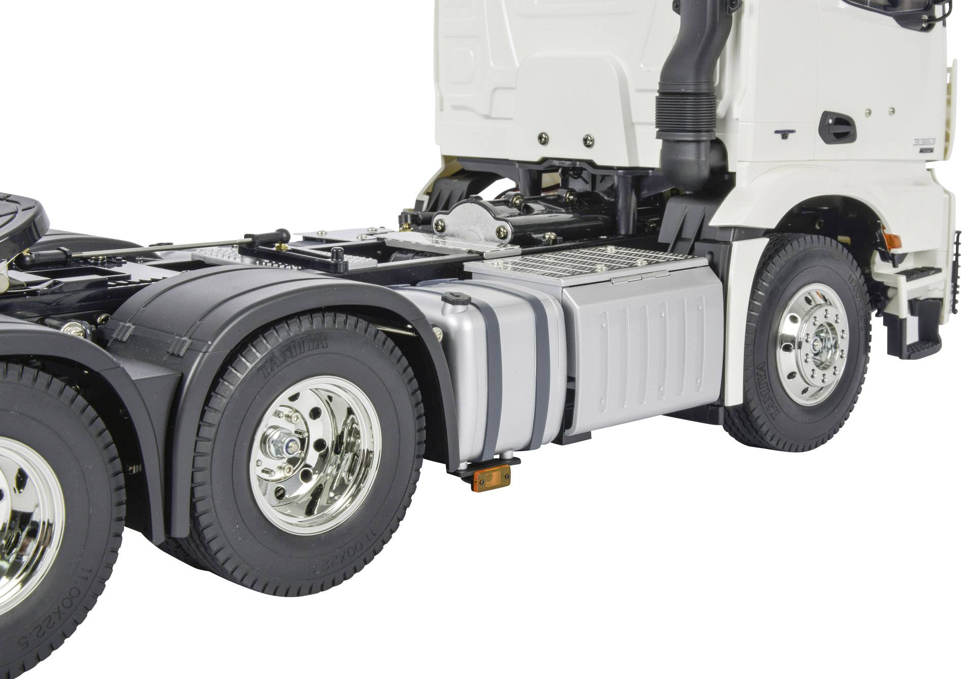 Un camion blanc sans remorque, vu de côté. Les grandes roues arrière et une partie de la carrosserie sont visibles.