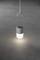 Une lampe grise suspendue éclaire une zone circulaire sur un sol sombre.