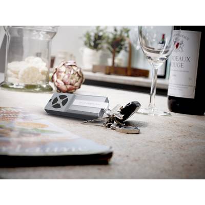 Bouteille de vin de Bordeaux rouge, verre à vin et clé sur une table. Un décor d'artichaut et un magazine en arrière-plan.