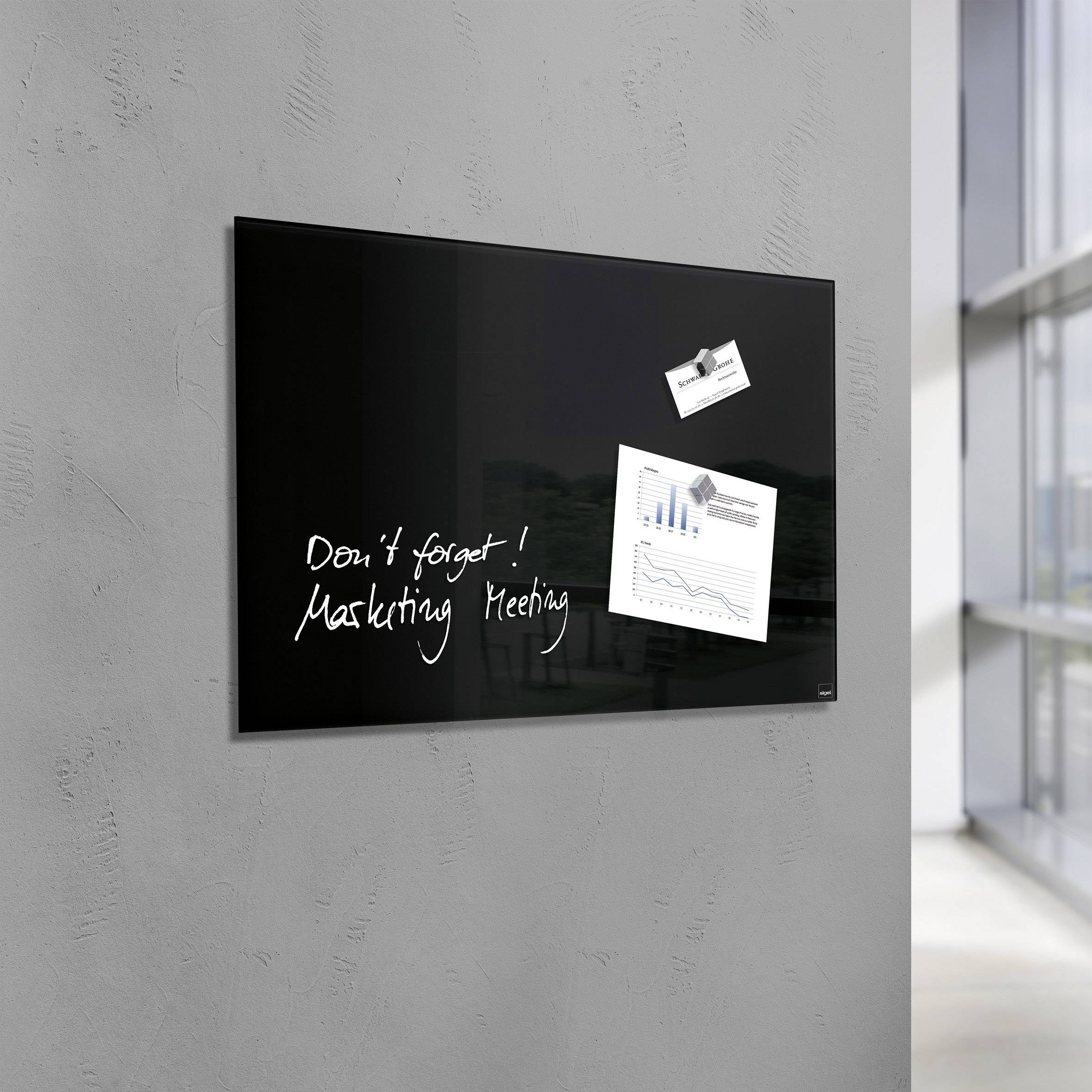 Tableau blanc noir sur un mur gris avec une note manuscrite 'N'oubliez pas ! Réunion marketing', accompagné de deux graphiques affichés à côté.