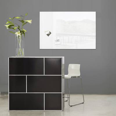 Un espace moderne et minimaliste avec un comptoir noir, sur lequel repose un vase de fleurs, et une chaise blanche sur le côté.