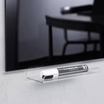 Un surligneur noir est posé sur une étagère murale transparente sous une télévision, installée dans une pièce moderne.