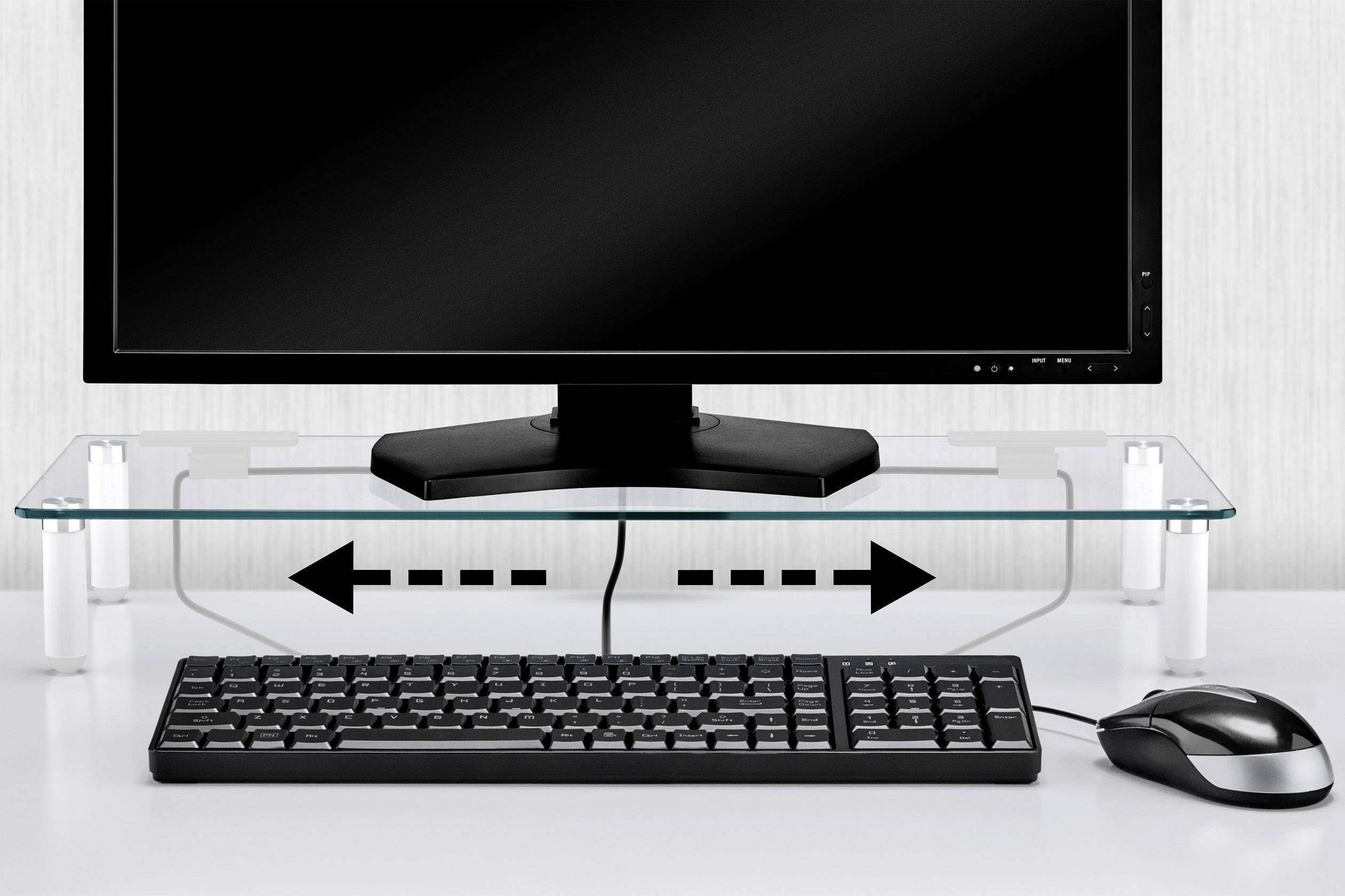Un écran d'ordinateur est posé sur un support en verre, au-dessus d'un clavier. Des flèches indiquent à gauche et à droite sous l'écran qu'un espace est prévu pour le clavier.
