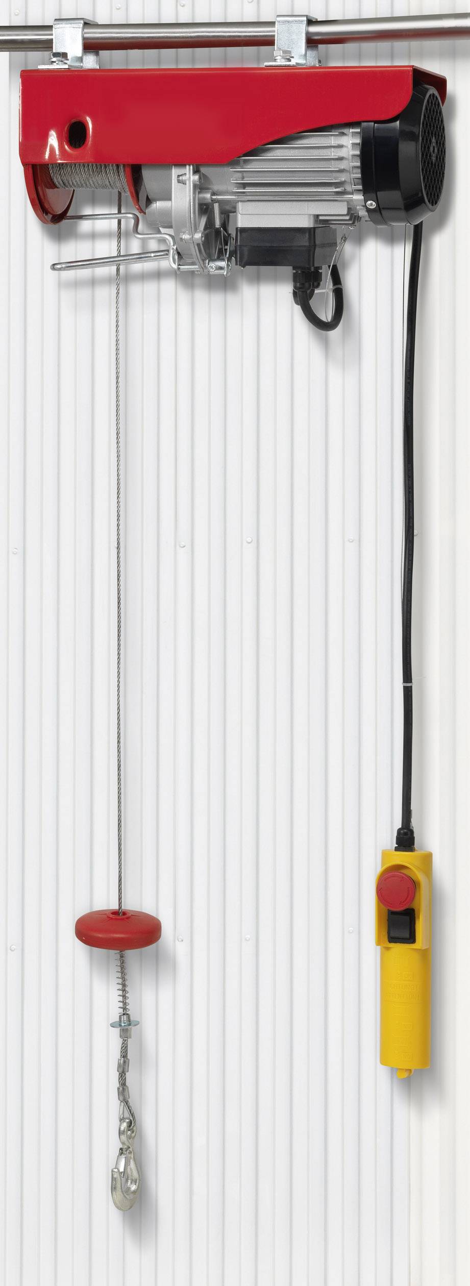 Treuil électrique à câble métallique avec boîtier rouge, télécommande jaune et câble en métal. Fixé sur un mur blanc.