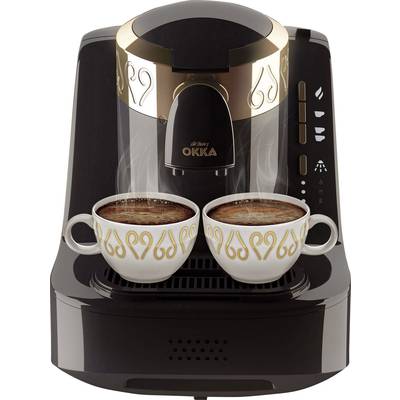 Une machine à café noire avec des ornements dorés, préparant deux tasses de café turc couvertes de mousse.