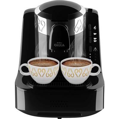 Machine à café noire prépare deux tasses de café avec de la mousse fumante. Les tasses ont des ornements dorés ondulants.