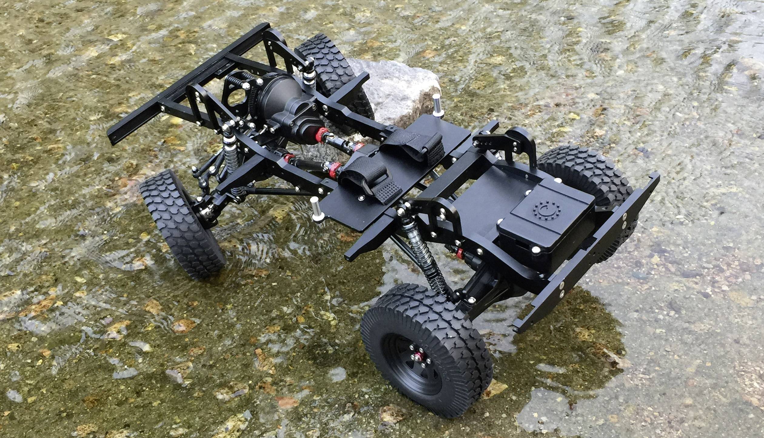 Un modèle d'un véhicule tout-terrain noir sans carrosserie sur un terrain rocailleux.