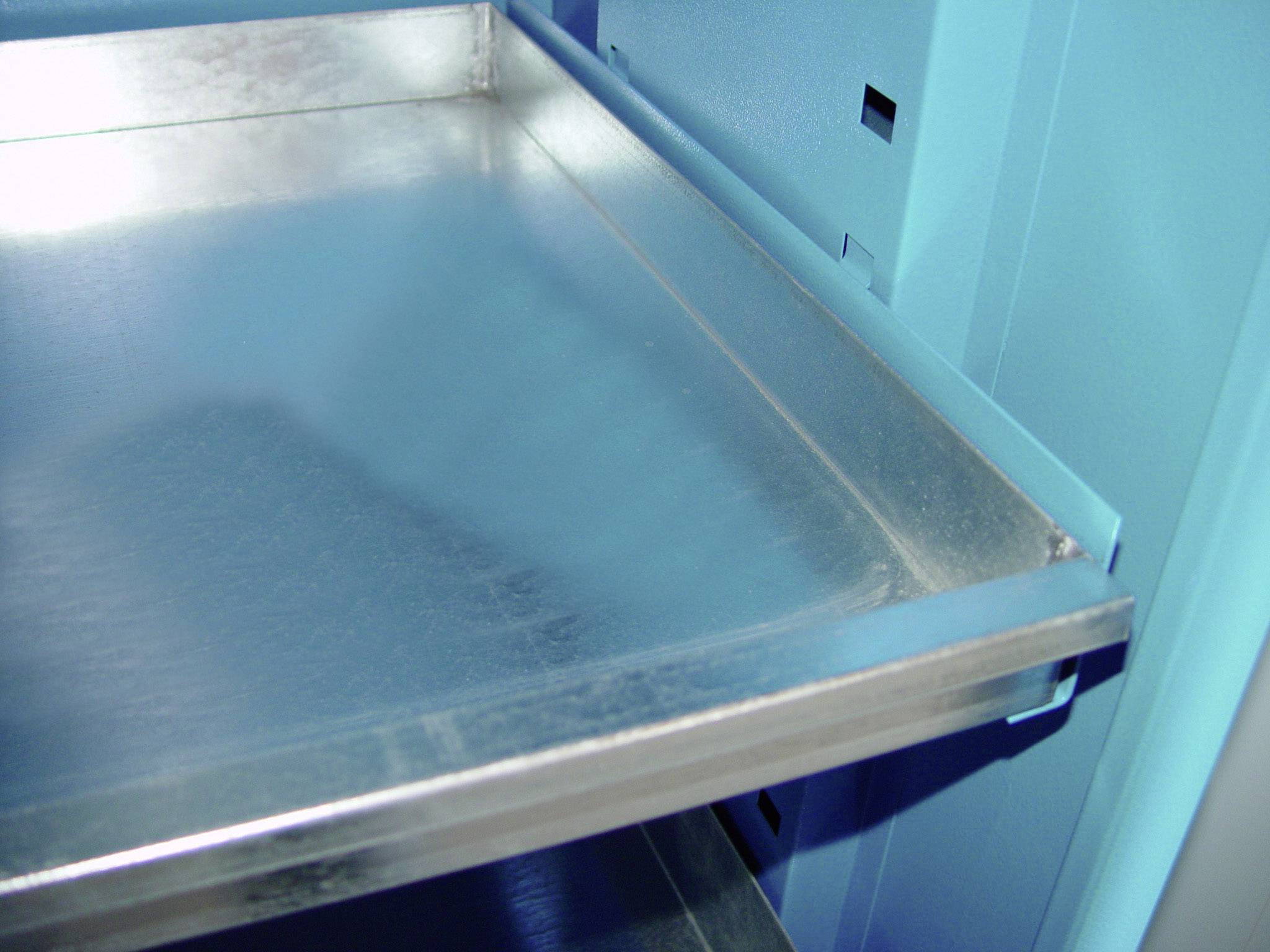 Tiroir métallique dans une armoire bleue, partiellement sorti, révélant l'effet de surface lisse et brillant.