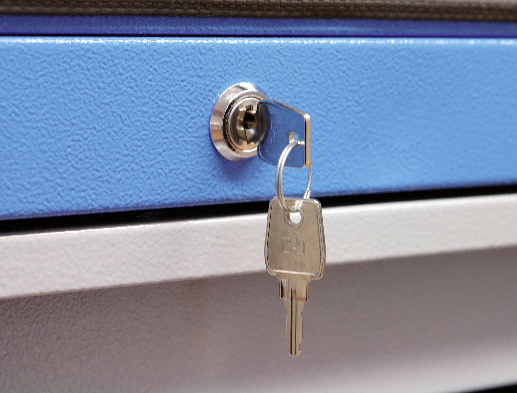 La clé est insérée dans un verrou métallique bleu situé sur un tiroir. L'anneau de la clé porte une étiquette sans texte visible.