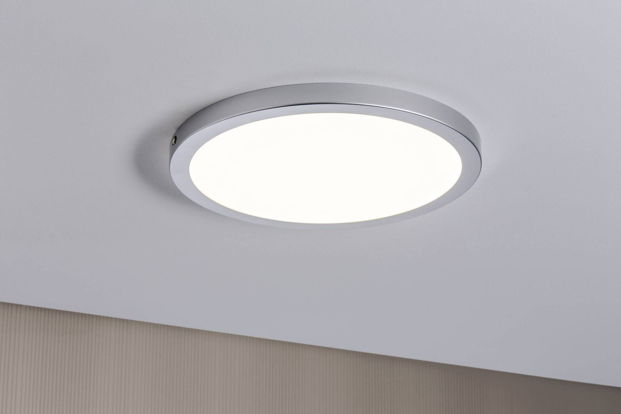 Plafonnier rond avec cadre métallique diffusant une lumière uniformément répartie, installé sur un plafond blanc.