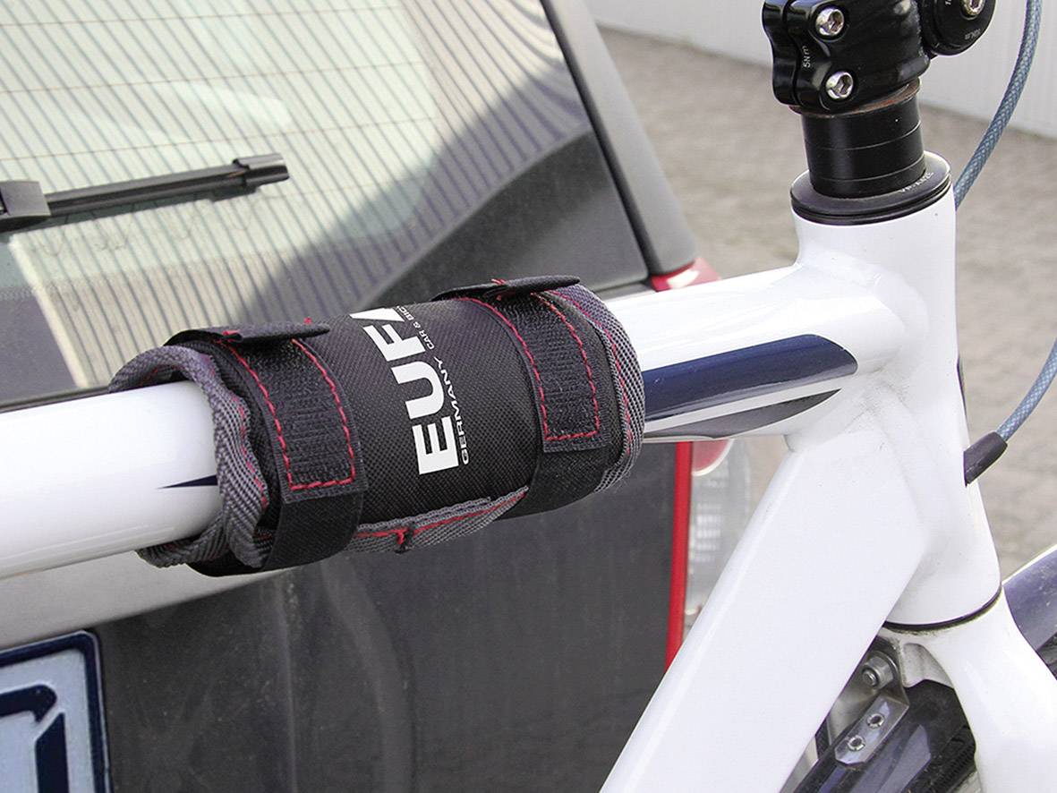 Cadre de vélo avec un coussin noir sur le tube supérieur. Une voiture floue en arrière-plan. Le coussin protège le cadre pendant le transport.