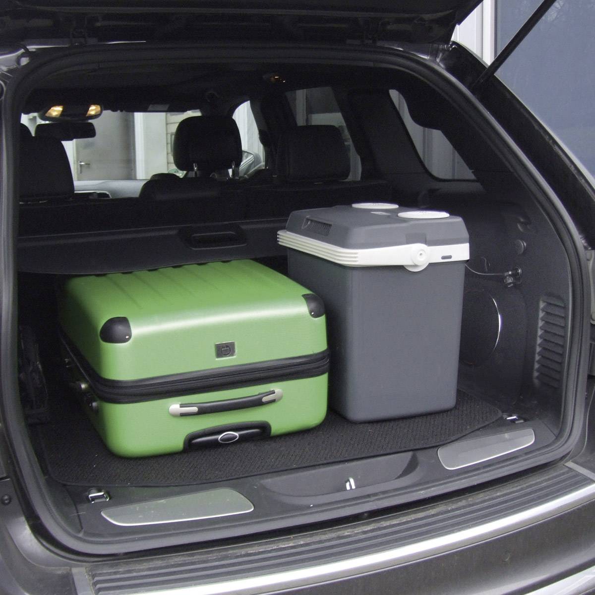 Coffre d'une voiture contenant une grande valise verte et un glacière grise.