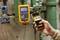Une main tient un smartphone affichant une indication de pression de '100,00 psi'. Des équipements techniques sont visibles en arrière-plan.