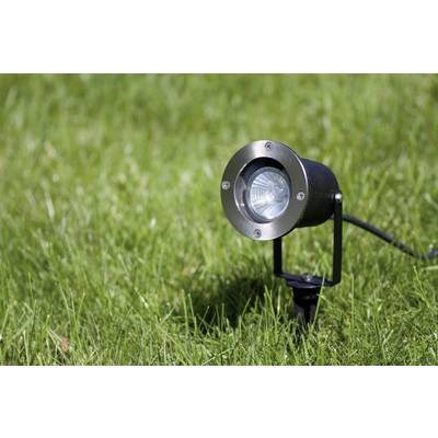 Un projecteur noir est positionné sur un gazon vert et dirigé vers le haut pour un éclairage vers le ciel.