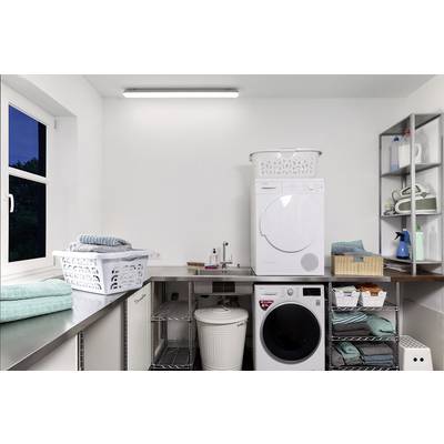 Buanderie avec machine à laver, sèche-linge, plusieurs paniers à linge, étagères contenant des produits de nettoyage et des serviettes pliées.