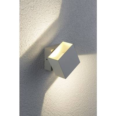 Applique murale moderne et minimaliste au design géométrique projetant une lumière chaleureuse sur un mur gris texturé.