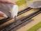 Une main répand du ballast de chemin de fer sur des rails. Conception détaillée d'un paysage ferroviaire miniature, avec un accent sur le travail de voie ferrée.