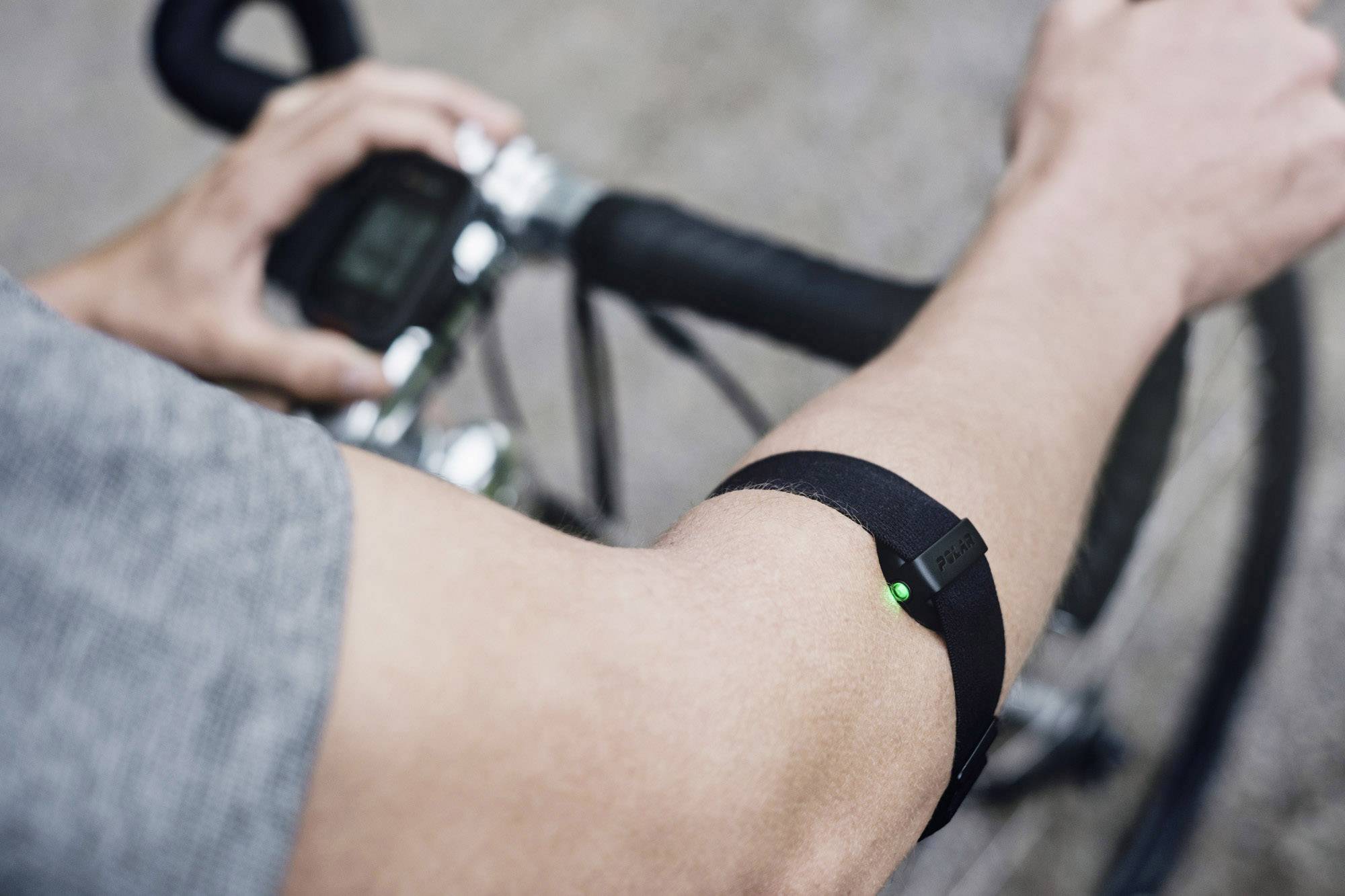 Une personne fait du vélo et porte un bracelet avec une lumière verte pulsante, qui est probablement un appareil de fitness ou de santé.