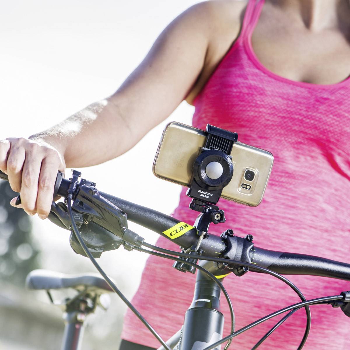 Une personne en tenue de sport fait du vélo tout en utilisant un smartphone fixé sur un support de guidon.