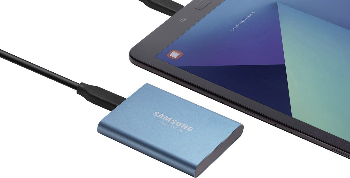Une disque dur externe bleue de Samsung est connectée à une tablette via un câble USB, affichant une image de fond géométrique.