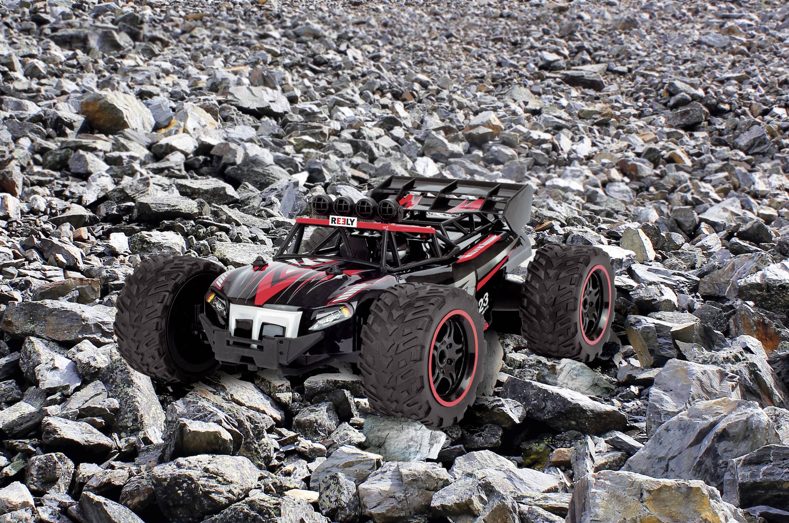 Une voiture télécommandée avec des pneus robustes roule sur une surface rocheuse et inégale, symbolisant les capacités tout-terrain.
