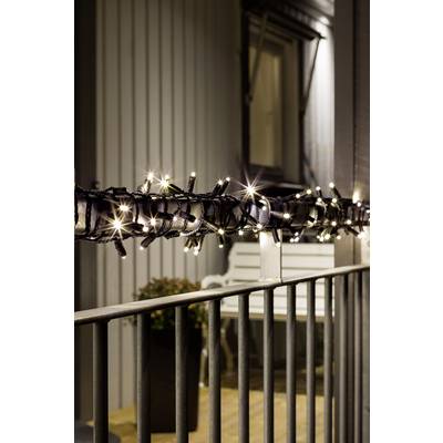 Guirlande lumineuse blanche illuminant une rambarde la nuit, avec une fenêtre et un banc visibles en arrière-plan.