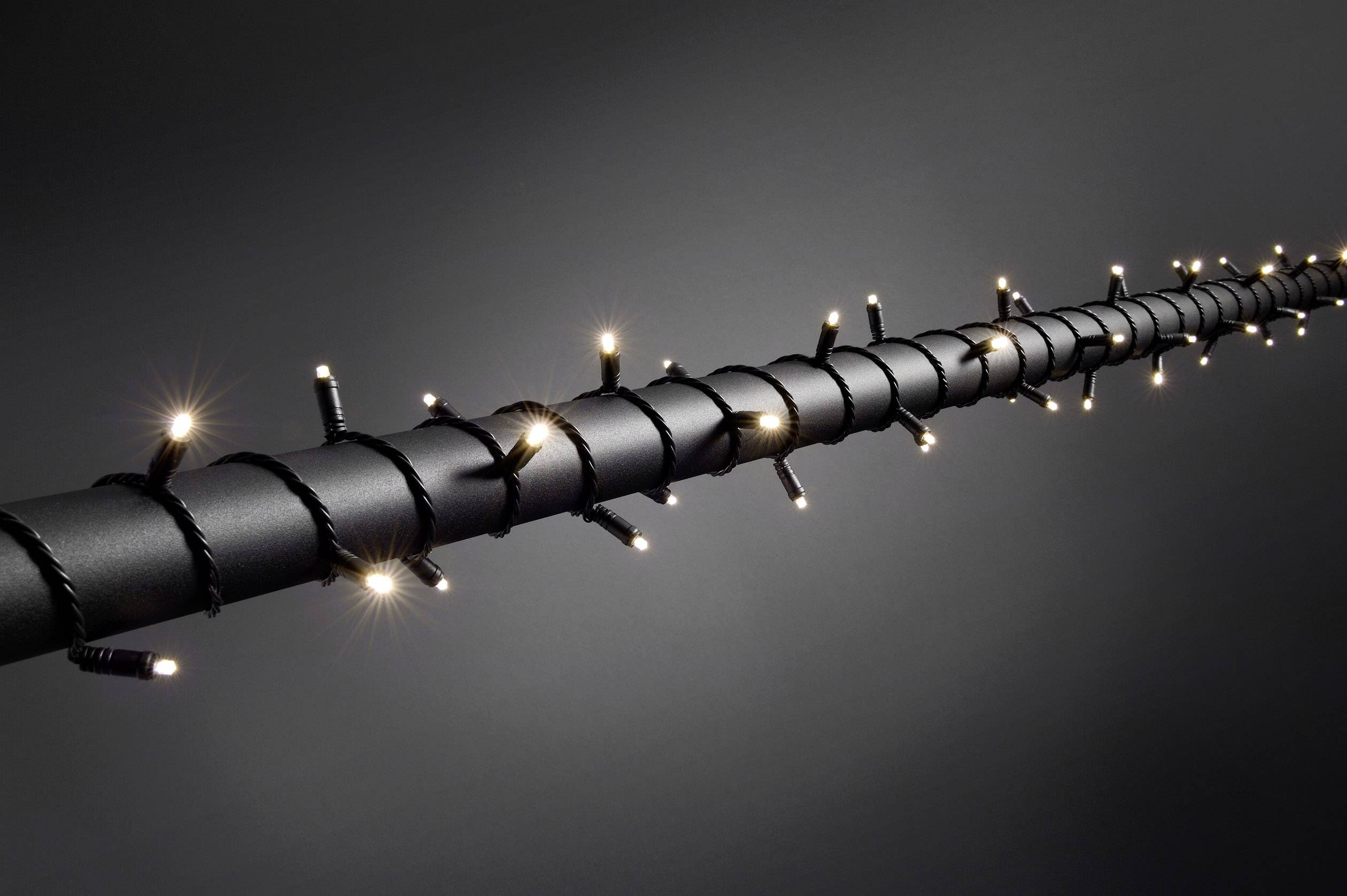 Une longue barre enroulée de petites lumières scintillantes, sur un fond sombre, crée une ambiance festive.