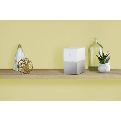 Une étagère décorée de manière minimaliste avec une sculpture géométrique, un cube moderne, une grande bouteille en verre et une succulente.