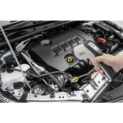 Un mécanicien automobile mesure la température d'un moteur avec un thermomètre infrarouge dans le compartiment moteur ouvert d'une voiture.