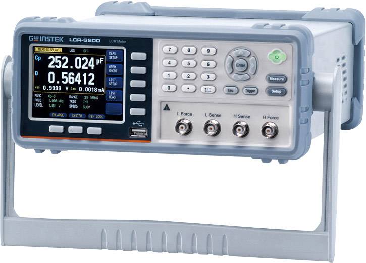 Un LCR-mètre posé sur une table, mesurant la capacité et la résistance. Sur l'écran sont visibles des valeurs de mesure et des boutons de commande.