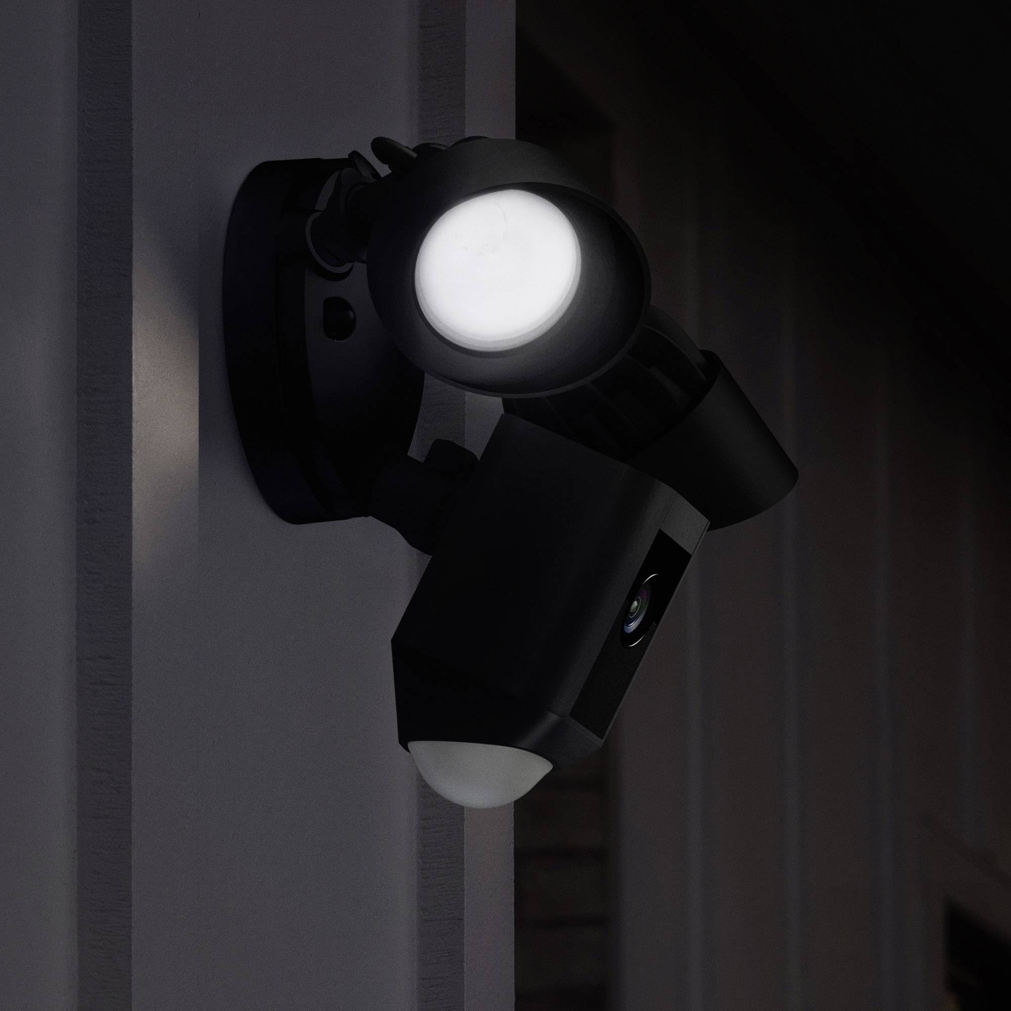 Une caméra de surveillance avec un éclairage intégré est montée sur un mur. La caméra est illuminée et semble active pendant la nuit.